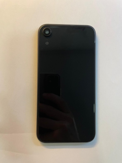 Smartphone preto com câmara e flash no canto superior esquerdo numa superfície branca