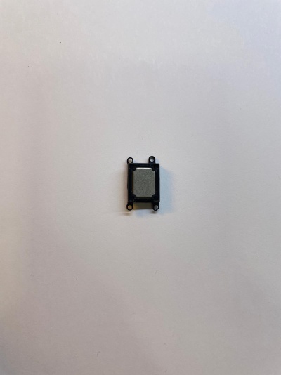 Peça eletrónica pequena quadrada preta e cinzenta em superfície branca