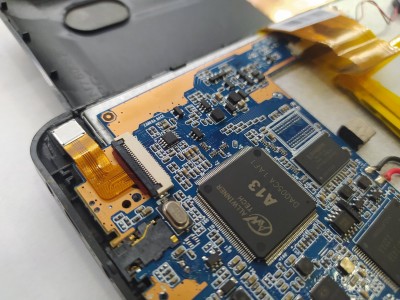 Placa eletrónica azul com componentes e etiquetas amarelas dentro de dispositivo aberto