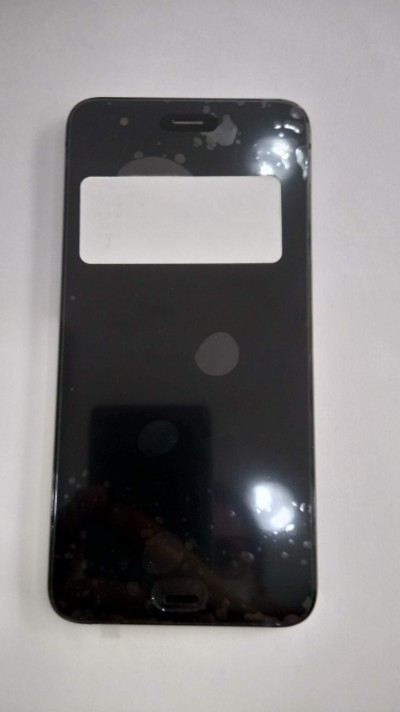 Smartphone preto com etiqueta branca no ecrã sobre superfície branca