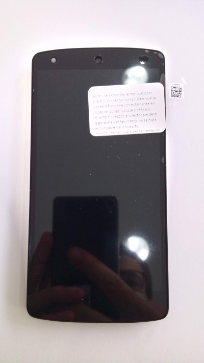 Smartphone preto com etiqueta branca no ecrã sobre fundo branco