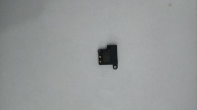 Pequeno componente eletrónico preto com contactos metálicos dourados sobre fundo branco