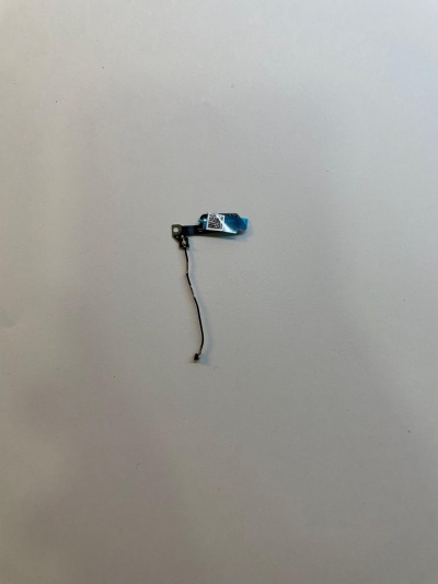 Peça eletrónica pequena com cabo fino sobre superfície branca