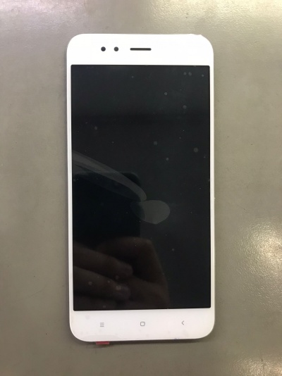 Smartphone branco com ecrã desligado sobre superfície cinzenta