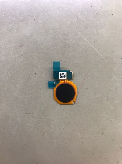 Peça eletrónica pequena com cores preta, amarelo e azul numa superfície cinzenta