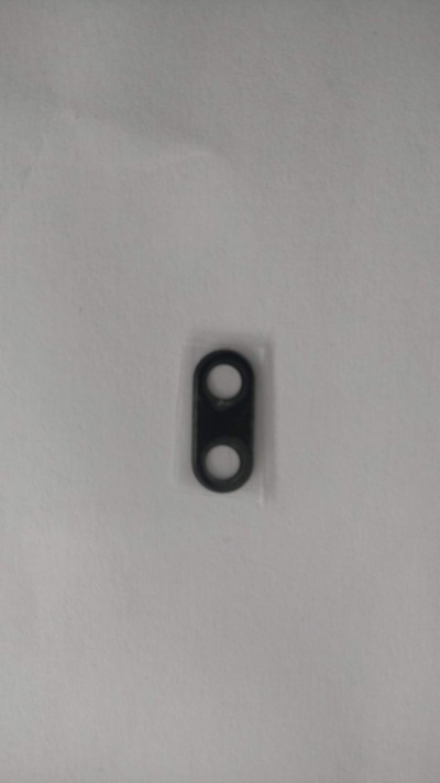 Peça oval preta com dois furos sobre fundo branco