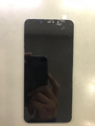 Ecrã de smartphone preto com manchas e riscos sobre superfície branca