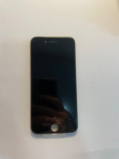 Smartphone preto com ecrã apagado numa superfície branca