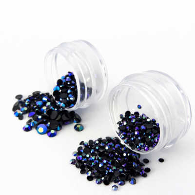 Frascos transparentes com cristais brilhantes azul e preto derramados