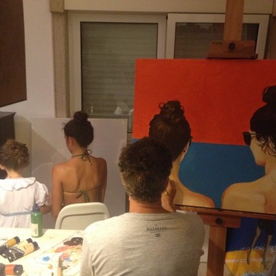 Três pessoas de costas com materiais de pintura e tela pintada num cavalete