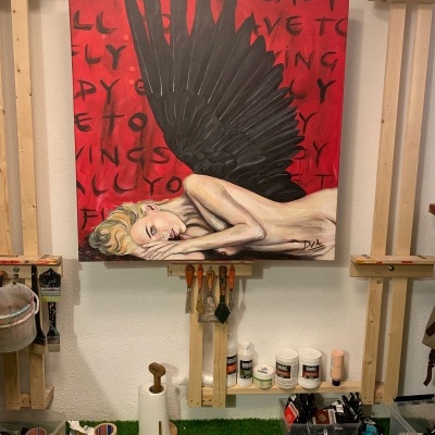 Pintura de uma mulher com asas negras num estúdio de arte