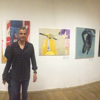 Galeria de arte com pinturas coloridas nas paredes e pessoas observando as obras