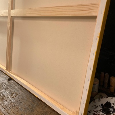 Tela de pintura com estrutura de madeira clara e paleta de tinta colorida ao lado