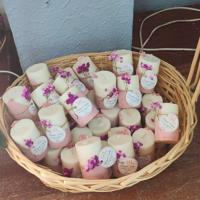 Cesto de velas decorativas brancas com base rosa e flores secas roxas