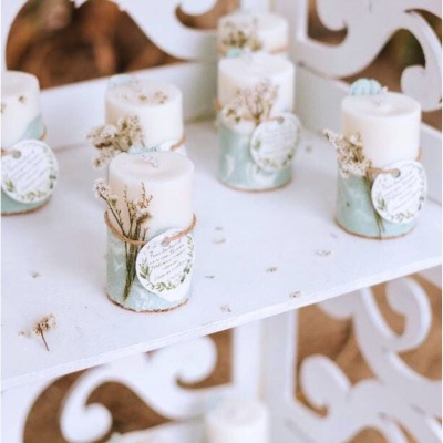 Pequenas velas decoradas com ramos secos sobre estante branca ornamentada