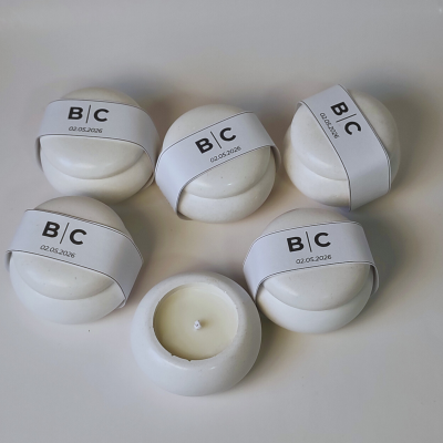 Cinco velas redondas com suporte branco e faixas brancas com texto B|C 02.05.2026