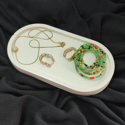 Anéis, colar com pérola e pulseiras coloridas em base branca sobre tecido preto