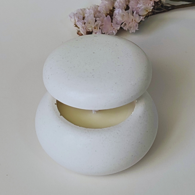 Castiçal redondo branco com vela amarela e flores secas cor-de-rosa