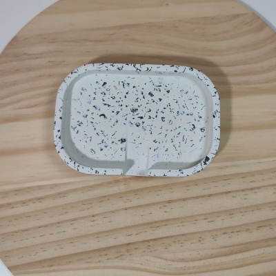 Bandeja pequena branca com manchas pretas sobre mesa de madeira clara