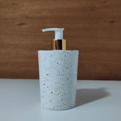 Dispenser de líquido branco com pontos pretos e bomba dourada e branca