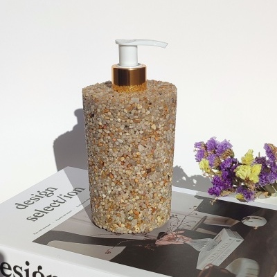 Dispenser de sabonete decorado com pedras sobre livros e flores secas