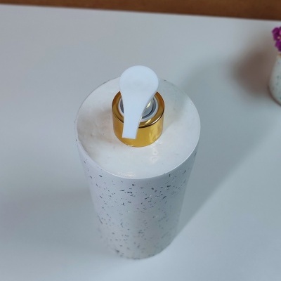 Garrafão branco com tampa dourada e válvula branca numa superfície branca.