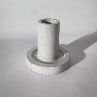 Objeto cilíndrico branco de cimento com base circular sobre superfície branca