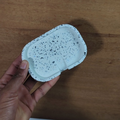 Cinzeiro retangular branco com manchas pretas numa mão sobre fundo de madeira