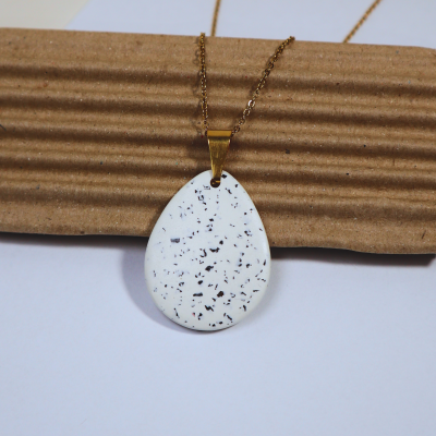 Colar com pendente gota branco e manchas pretas com corrente dourada
