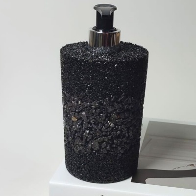 Dispenser preto áspero com tampa cromada sobre livro branco