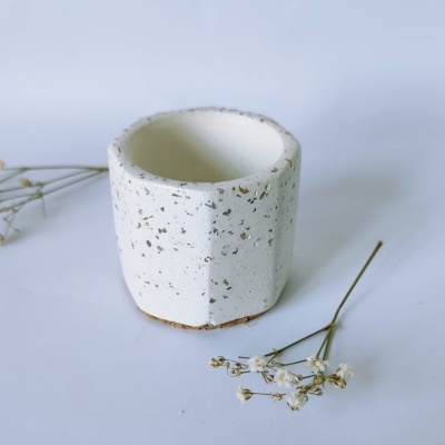 Vaso cerâmico branco rugoso com manchas castanhas e flores secas ao redor