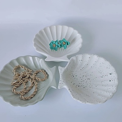 Três pratos brancos em forma de concha com acessórios variados