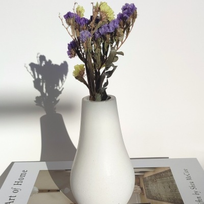 Vaso branco com flores secas em cima de um livro