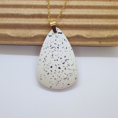 Colar dourado com pendente branco manchado