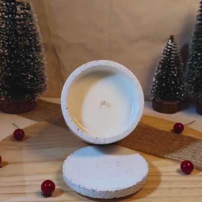 Vela branca em recipiente cinza claro com decoração natalícia