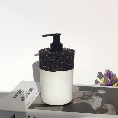 Dispenser de sabonete branco com topo preto texturizado sobre livro design selection com flores ao fundo