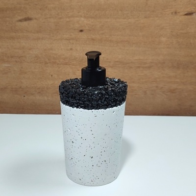 Dispenser de sabonete líquido branco com topo preto e textura de pedras.