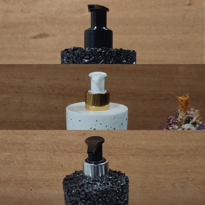 Três frascos dispensadores decorativos com padrões em pedra e tampas coloridas em fundo de madeira