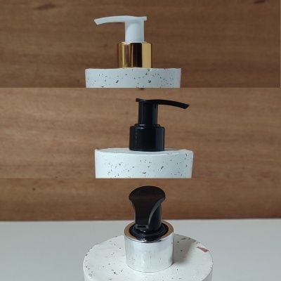 Três tampas de doseador de bomba empilhadas sobre bases brancas manchadas