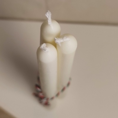 Três velas brancas cilíndricas amarradas com corda colorida