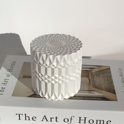 Vela branca texturizada sobre livro The Art of Home