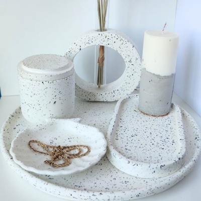 Conjunto de artigos de decoração em cerâmica branca com manchas pretas, incluindo pratos, frasco, suporte e castiçal com vela