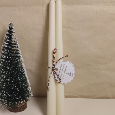 Par de velas brancas altas com etiqueta natalícia e mini árvore de Natal verde com neve artificial