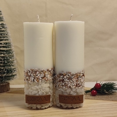 Duas velas decorativas brancas com pedras e etiqueta de couro DORVAL sobre mesa de madeira