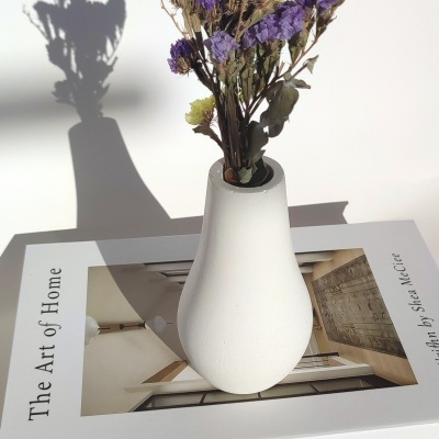 Vaso branco com flores secas sobre livro 'The Art of Home'