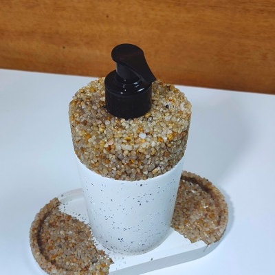 Frasco branco com dispenser preto decorado com pequenas pedras na tampa e base