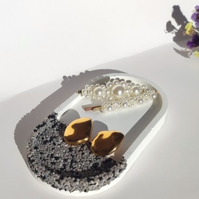 Brincos dourados e presilha branca com pérolas em suporte branco