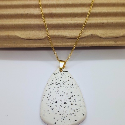 Colar dourado com pendente branco com manchas pretas