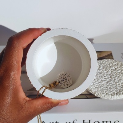 Caixa redonda branca com pendente de colar dentro sobre livro