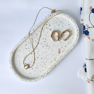 Colar dourado com pérola e brincos dourados em bandeja terrazzo branca